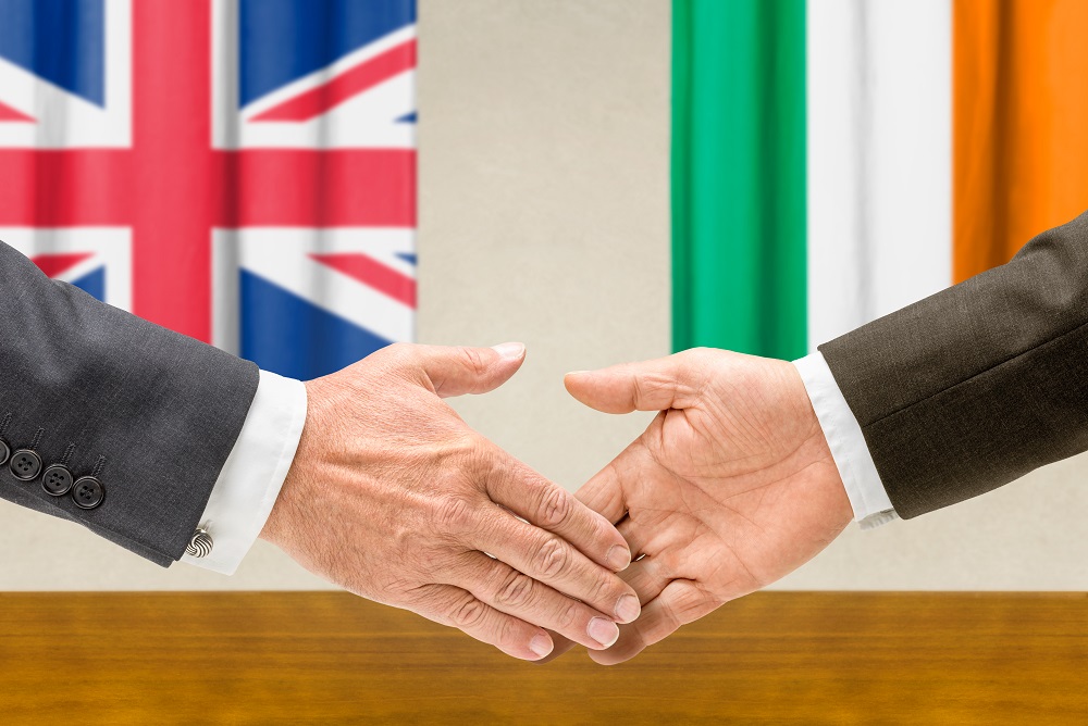 Handshake with British and Irish flags in background